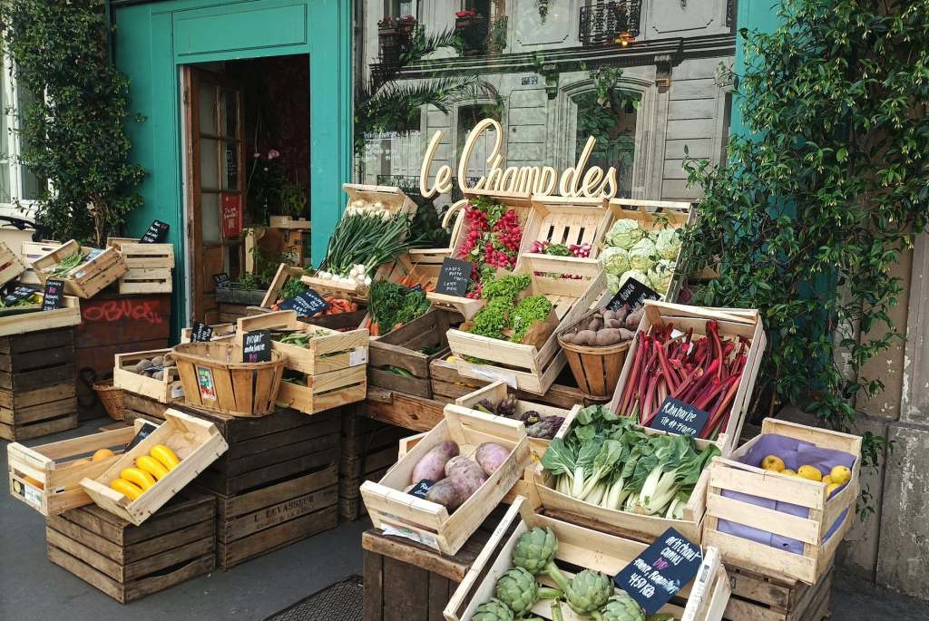 Some fruits and vegetables on display inside wooden crates by the door of a grocery store.